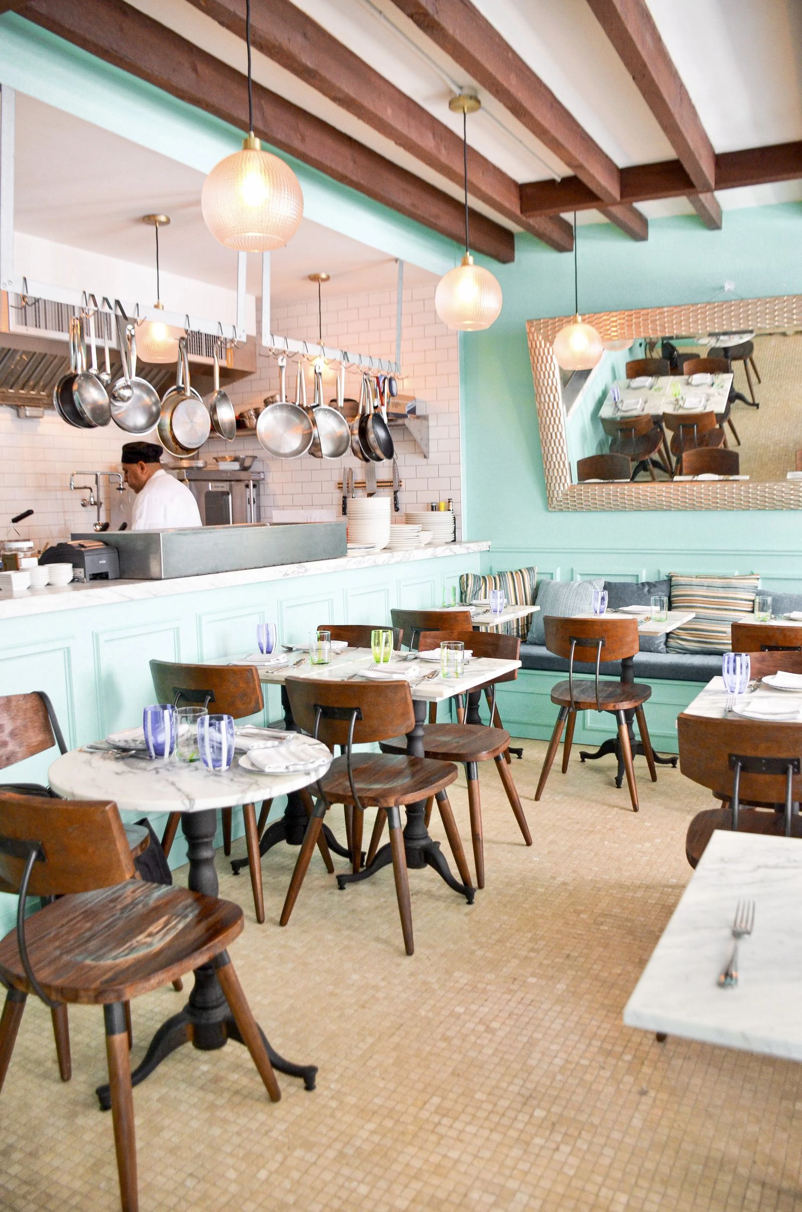 The Coco Shack dining room in Soho, chef at the pass beneath hanging copper pans